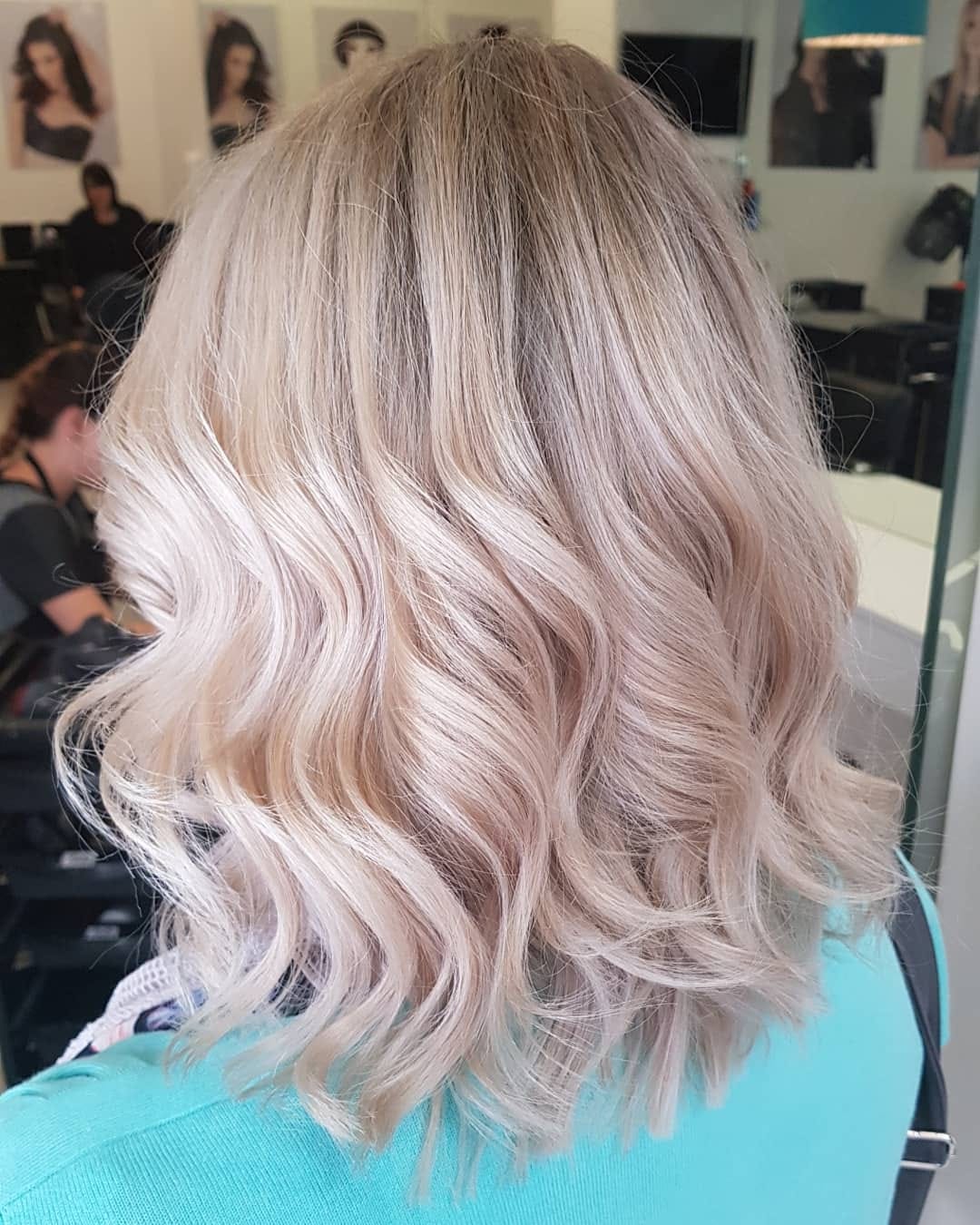A woman with blonde hair is sitting in a chair in a salon.