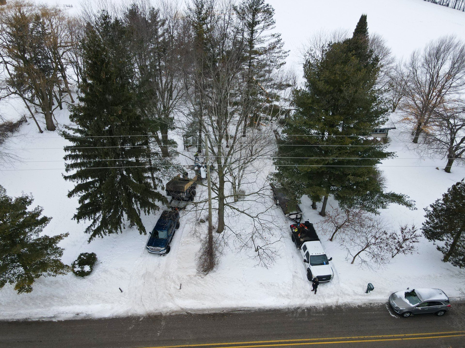 An aerial view of a snowy driveway with cars parked in the snow