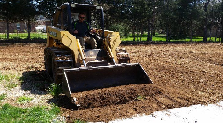 A man is driving a bulldozer in a dirt field.