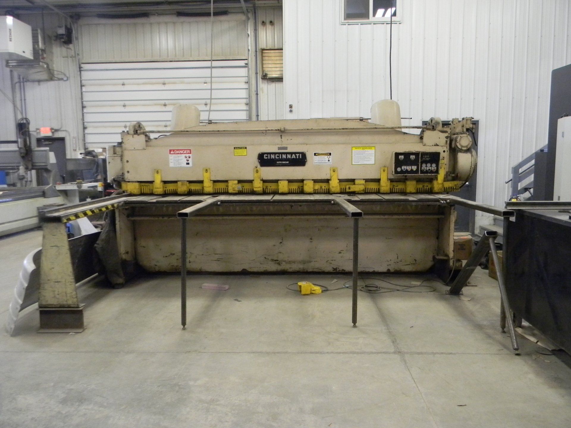 A machine is sitting on the floor in a room with a garage door in the background.