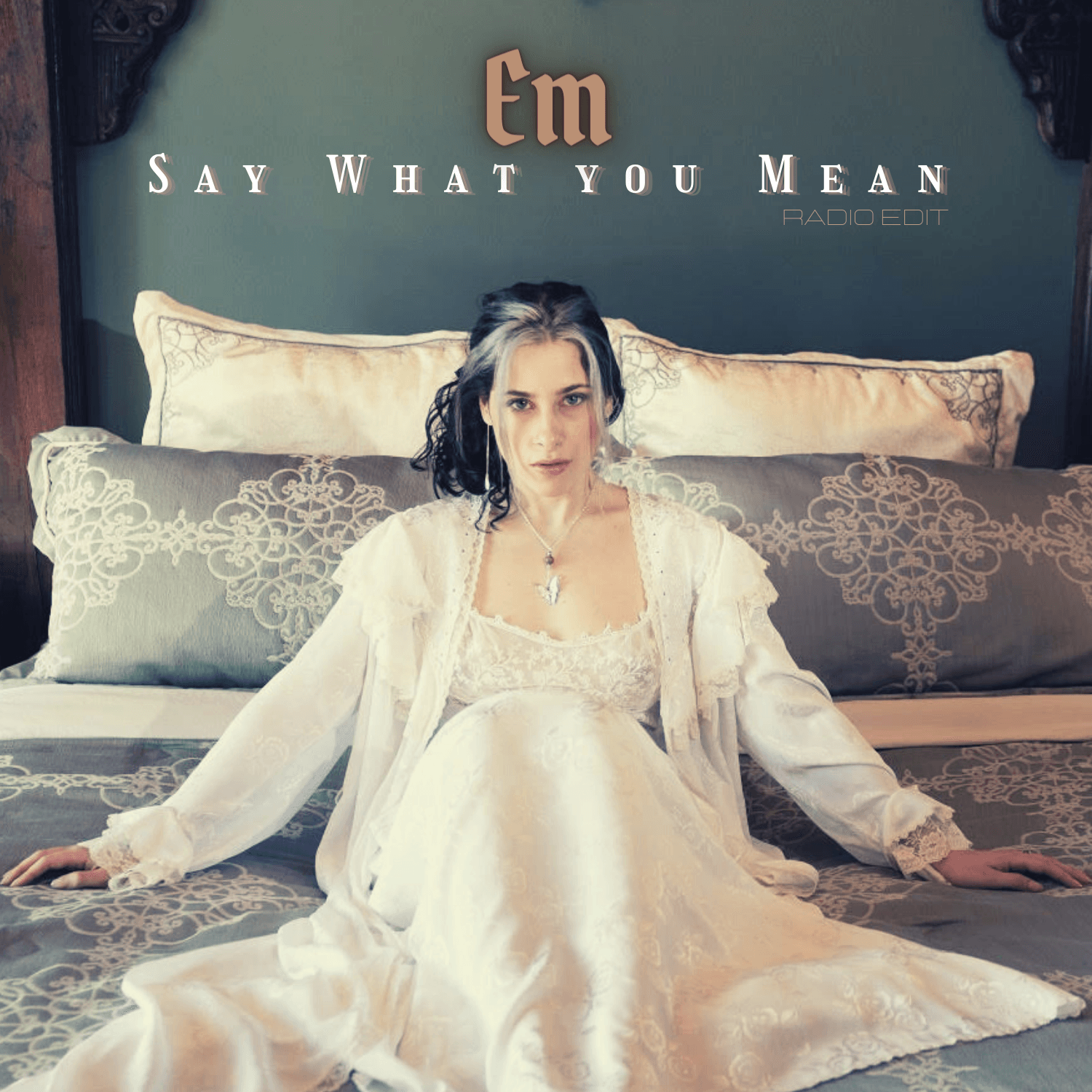 Woman in white dress sitting on a bed beneath the title “Em Say What You Mean”