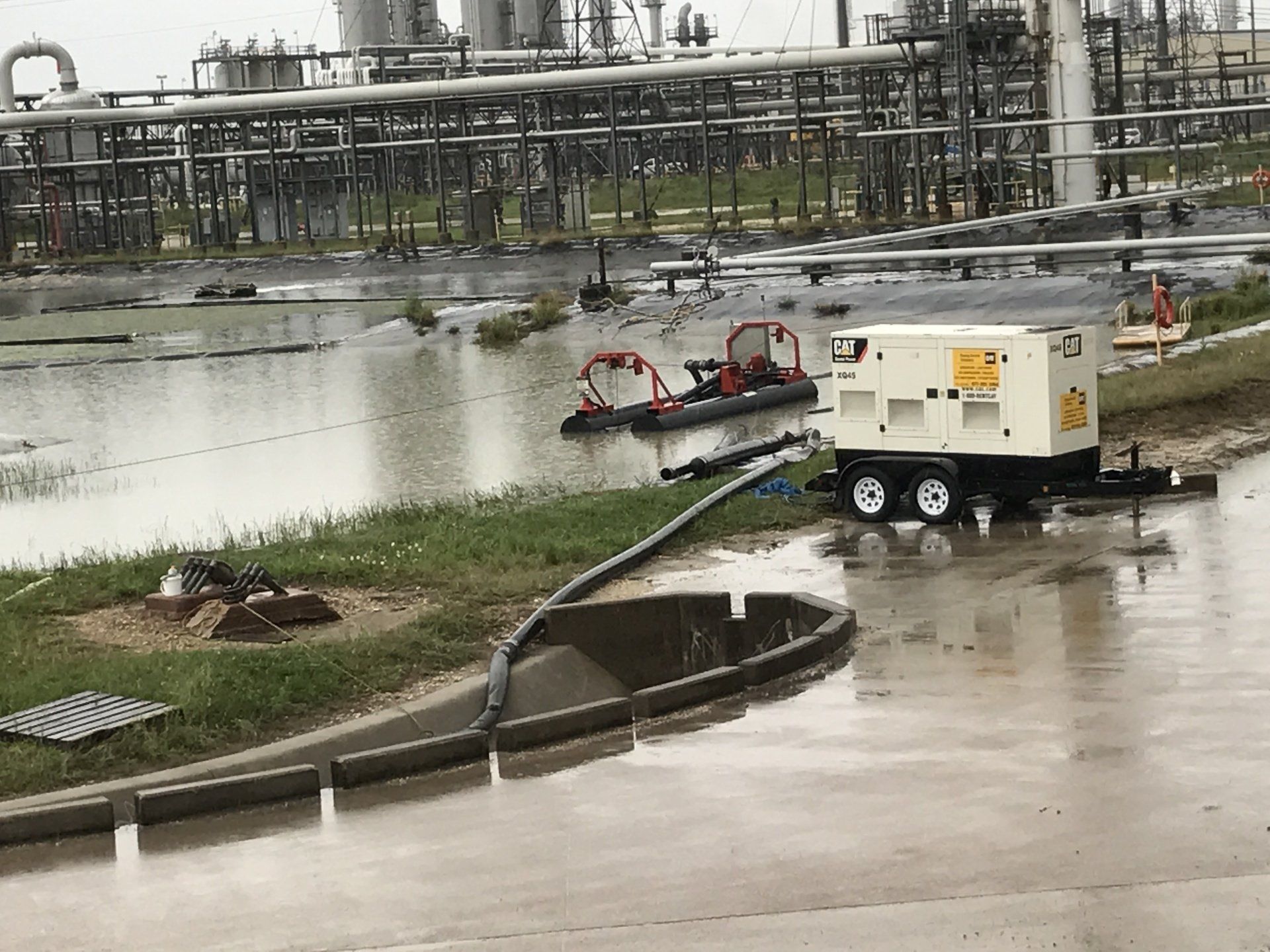 A trailer with a hose attached to it is parked in front of a flooded area.