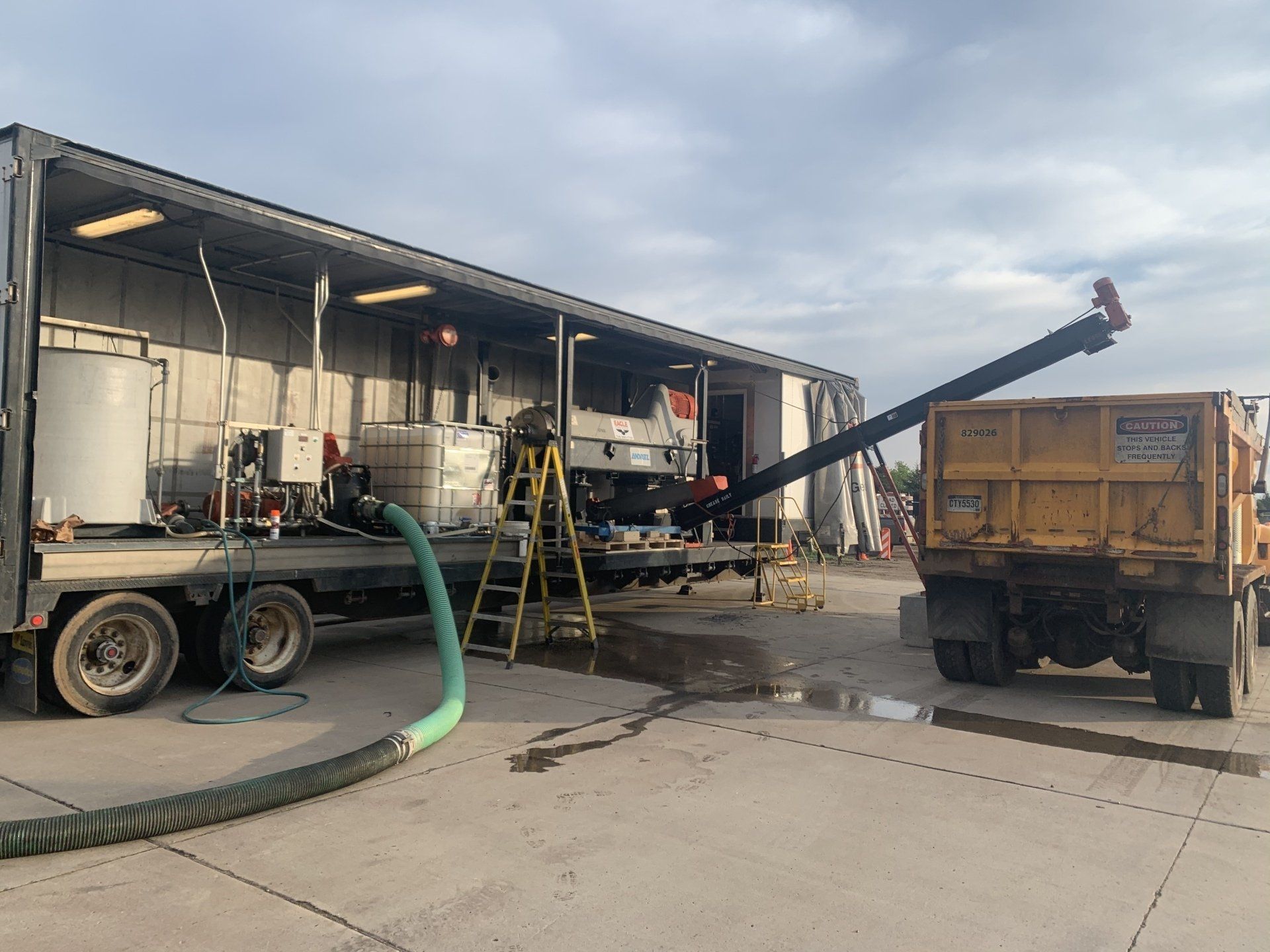 A truck with a hose attached to it is parked in front of a building.