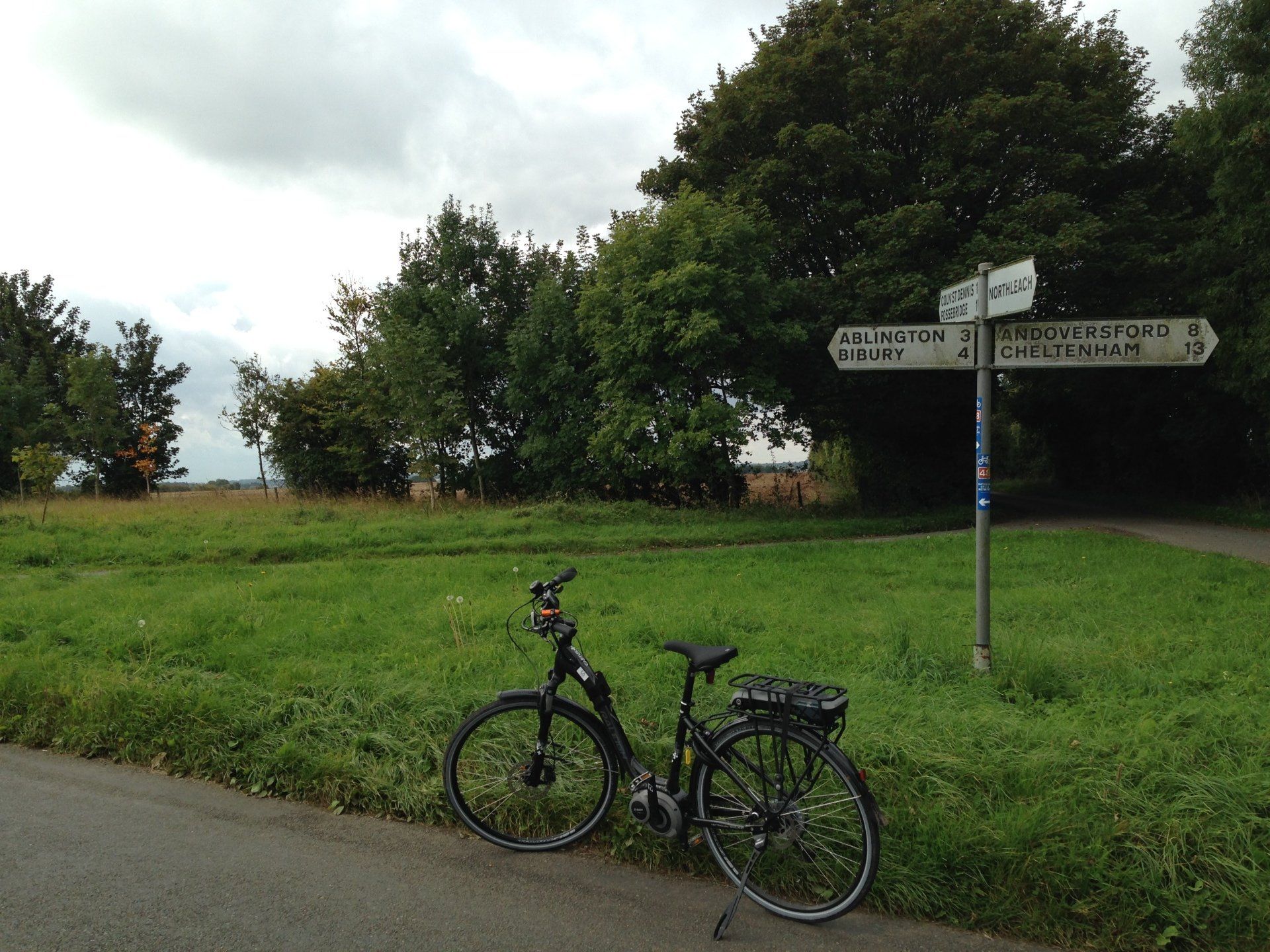 A bicycle is parked on the side of the road next to a street sign