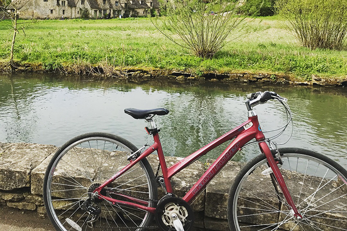 A red bicycle is parked on a stone wall next to a river.