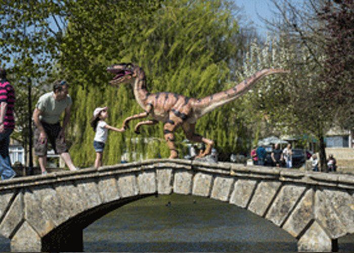 A statue of a dinosaur is standing on a stone bridge.