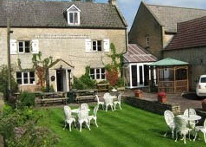 A large house with tables and chairs in front of it.
