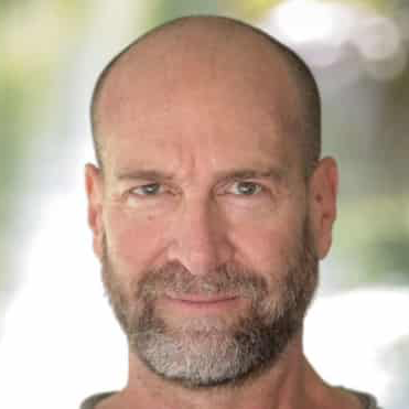 A bald man with a beard is smiling for the camera.