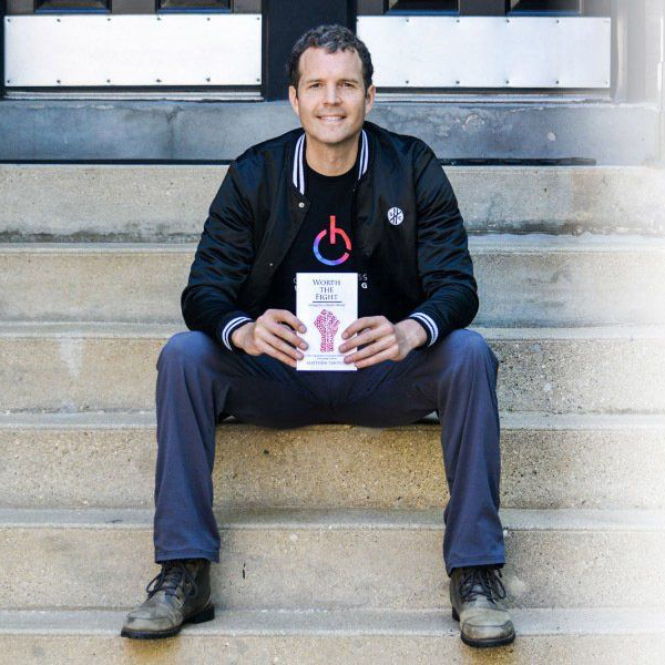 A man is sitting on a set of stairs holding a book