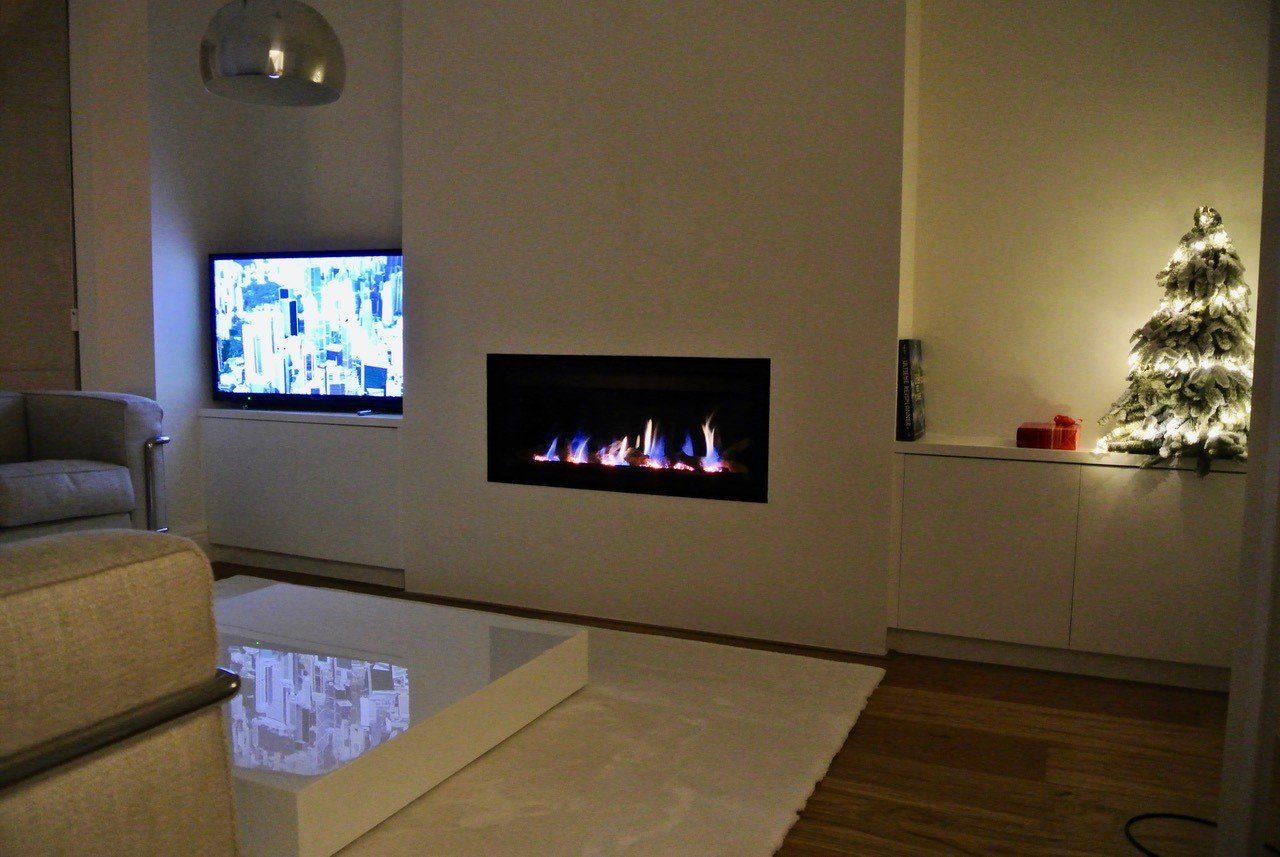 Modern living room with wall-mounted fireplace, TV, and lit Christmas tree