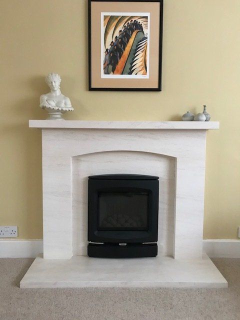 Modern black fireplace set within a white stone mantel beneath framed wall art