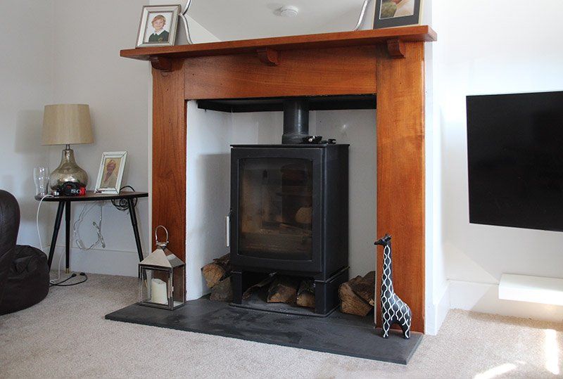 Cozy living room with black wood stove, wooden mantel, and rustic elements