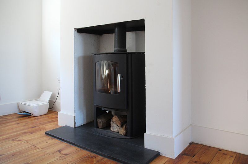 Warm living room featuring a wood stove, wooden mantel, and decorative accents