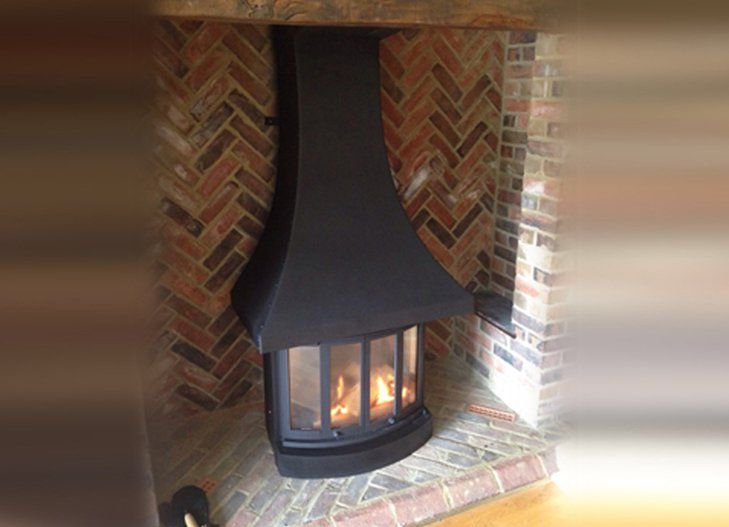 Curved black fireplace with glass panels set inside a herringbone brick surround