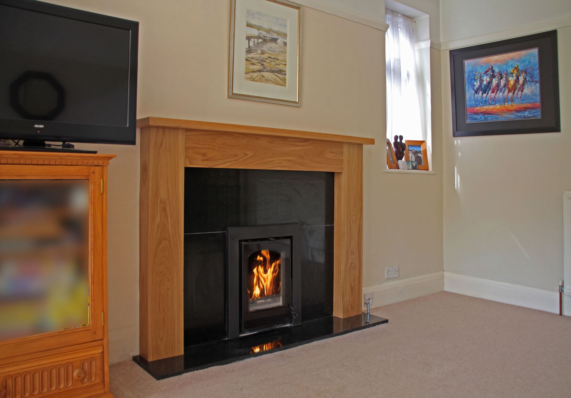 Wood-burning stove set in a wooden mantel with black hearth in a living room
