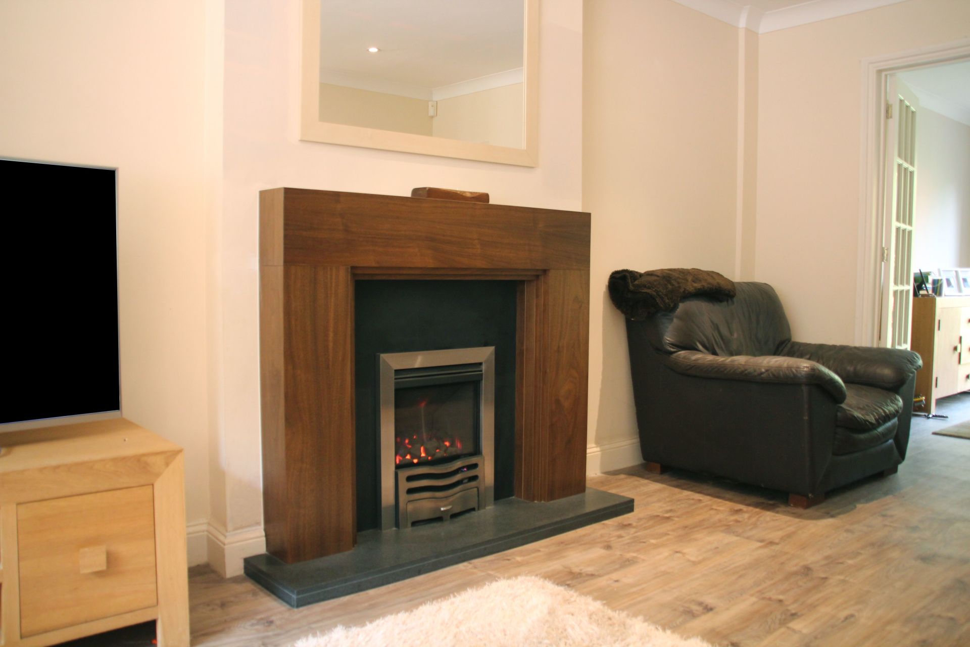 Modern electric fireplace with wooden surround in a cosy living room setting