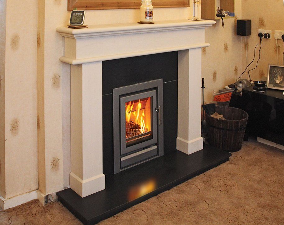 Compact wood-burning stove in a white mantel with black hearth in a cosy living room