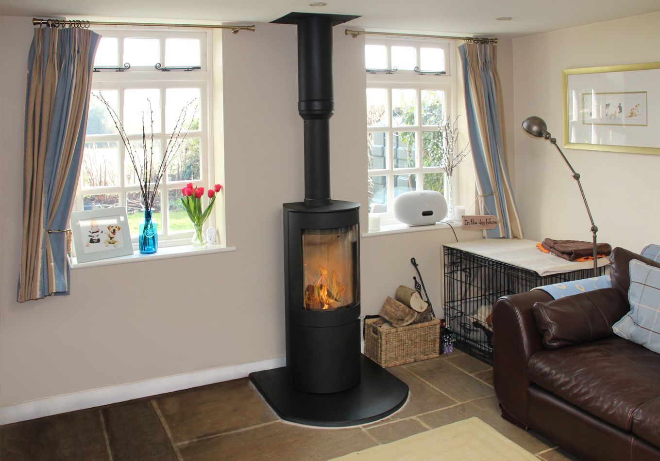 Freestanding black wood stove between windows in a bright living room with modern decor