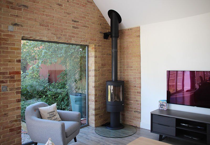 Elegant wood stove with glass panel and natural greenery visible through window