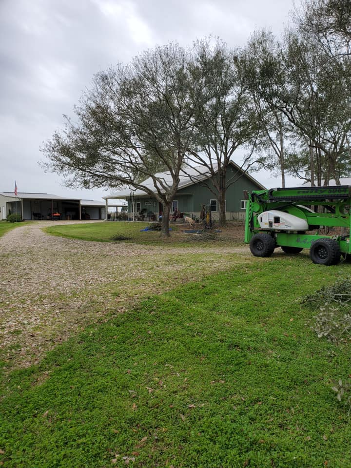 Rural farmhouse yard with trees, gravel driveway, and a green tractor under cloudy skies