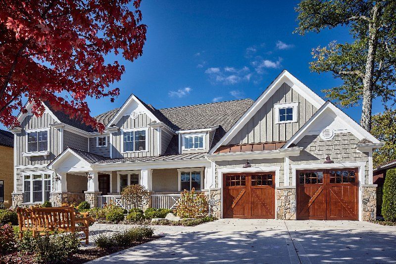 A large house with two garage doors and a bench in front of it