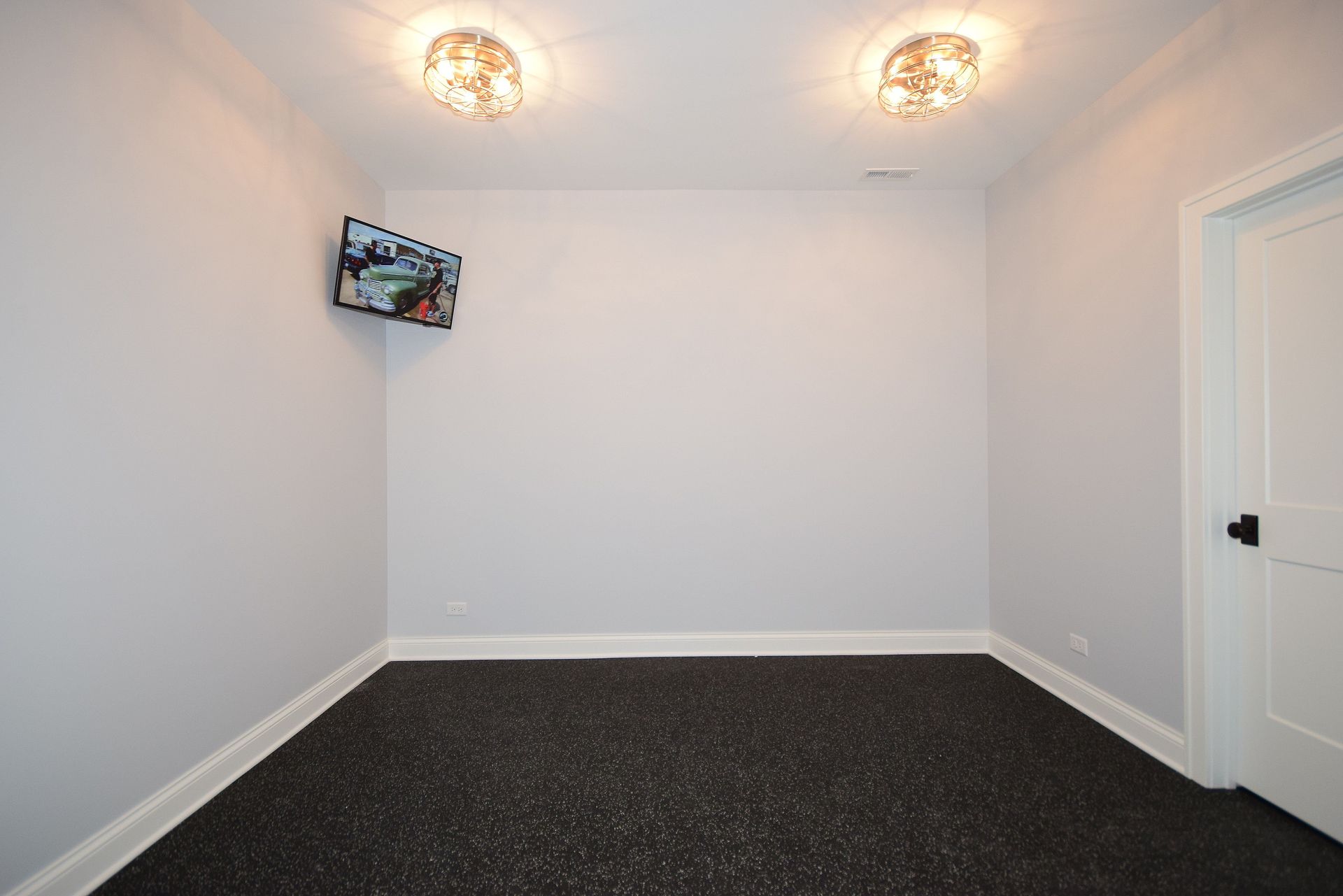 An empty room with a black carpet and white walls