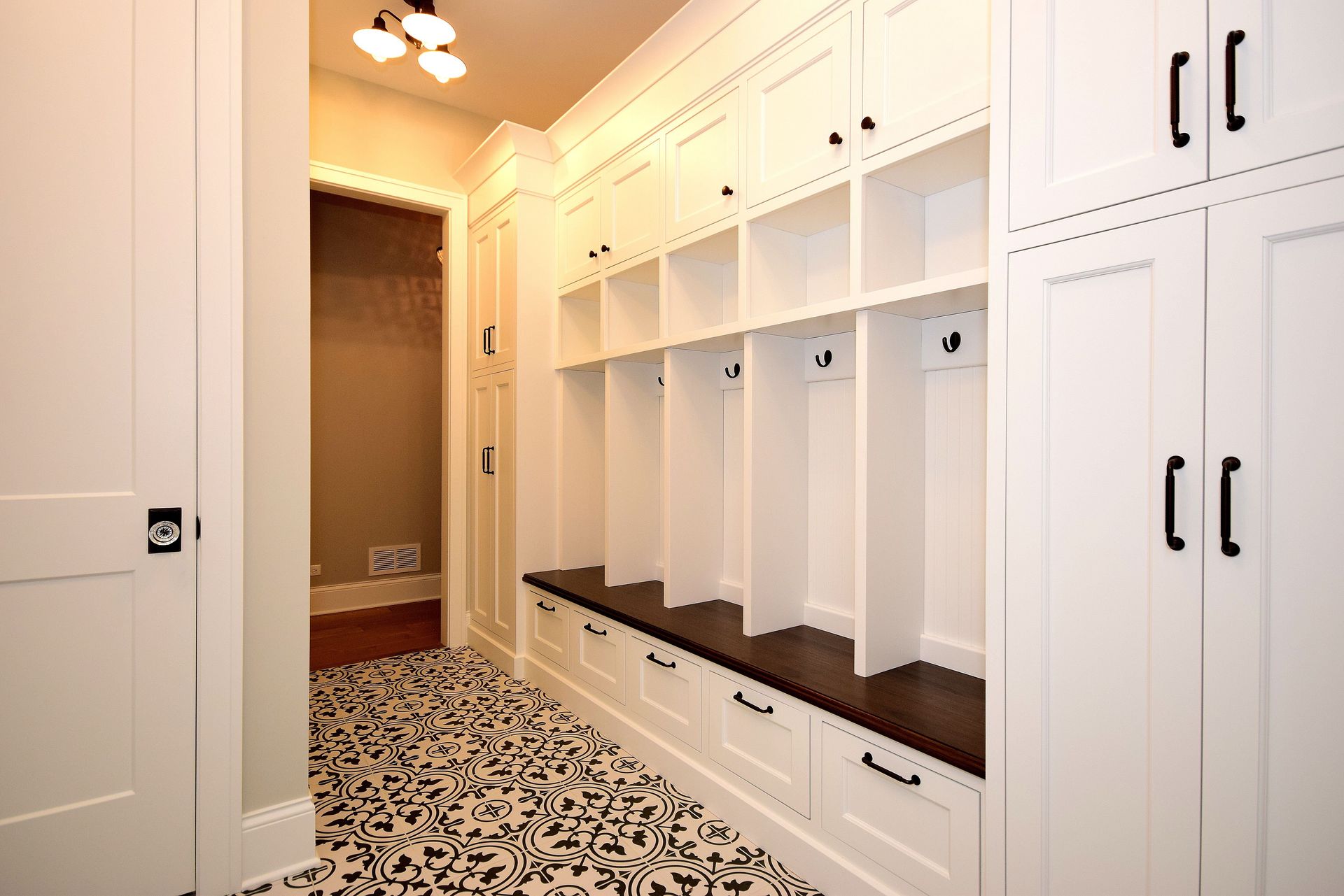 A walk in closet with white cabinets and a bench.