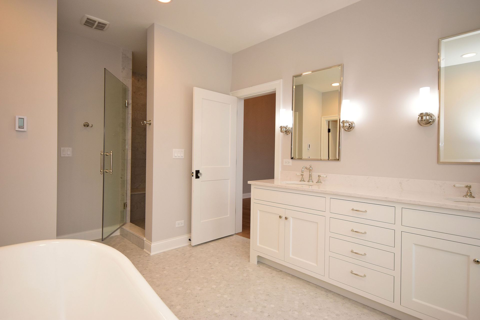A bathroom with a bathtub , sinks , mirrors and a walk in shower.