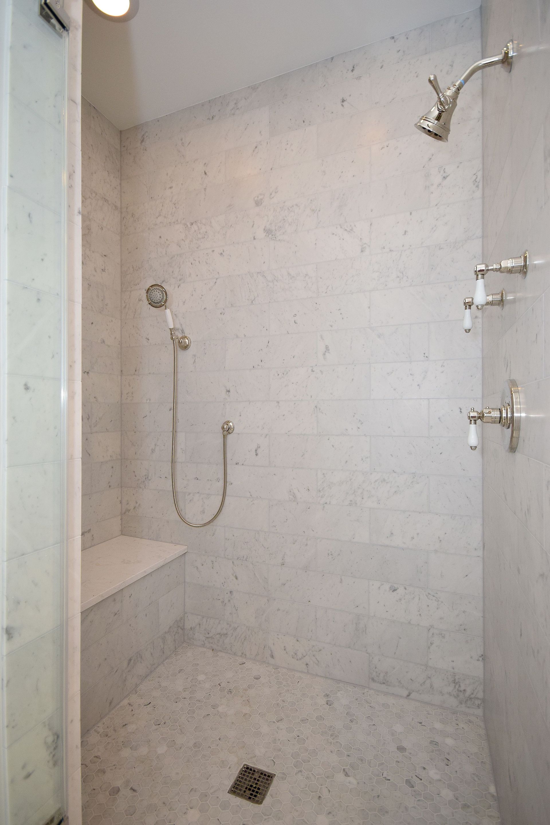 There is a shower with a bench and a shower head.