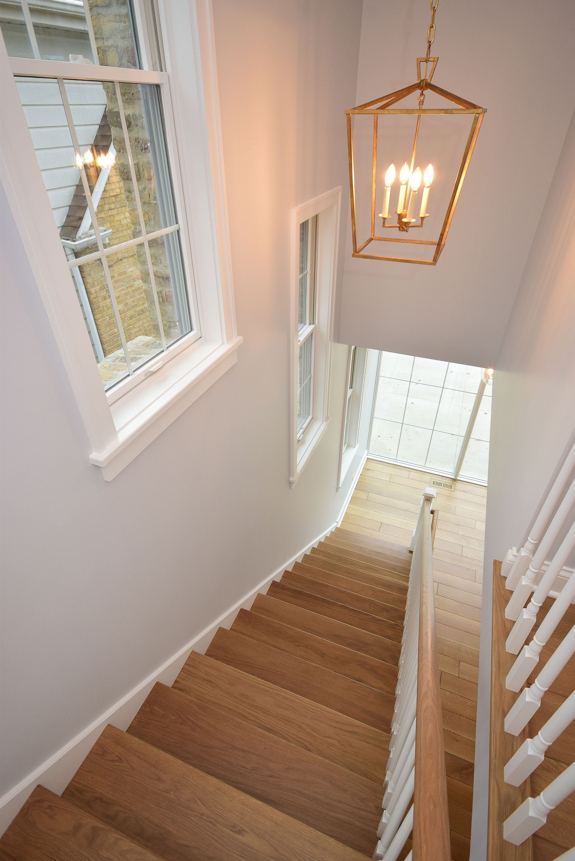 A staircase with a lantern hanging from the ceiling and a window.