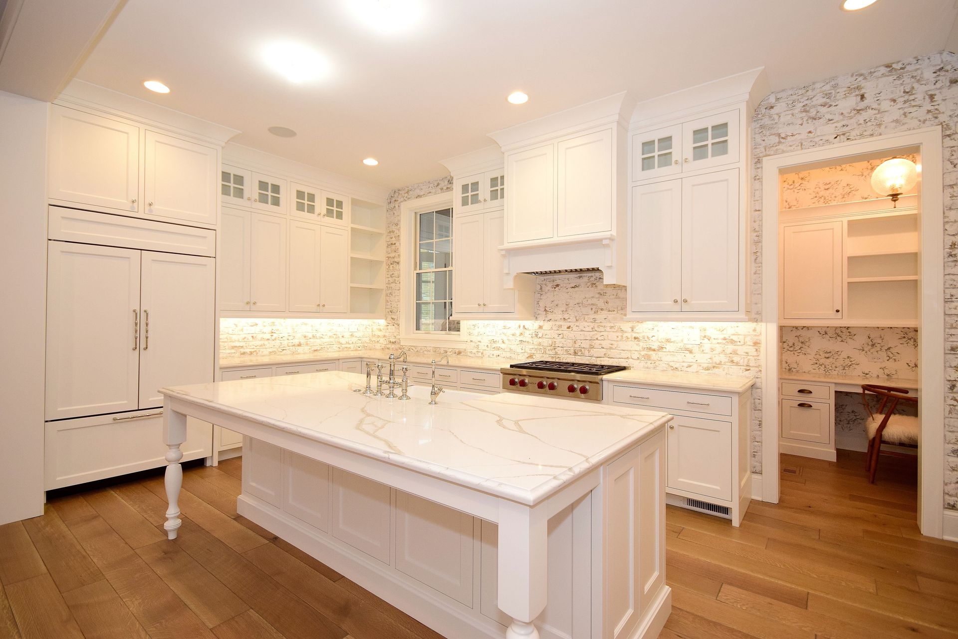 A kitchen with white cabinets and a large island in the middle.