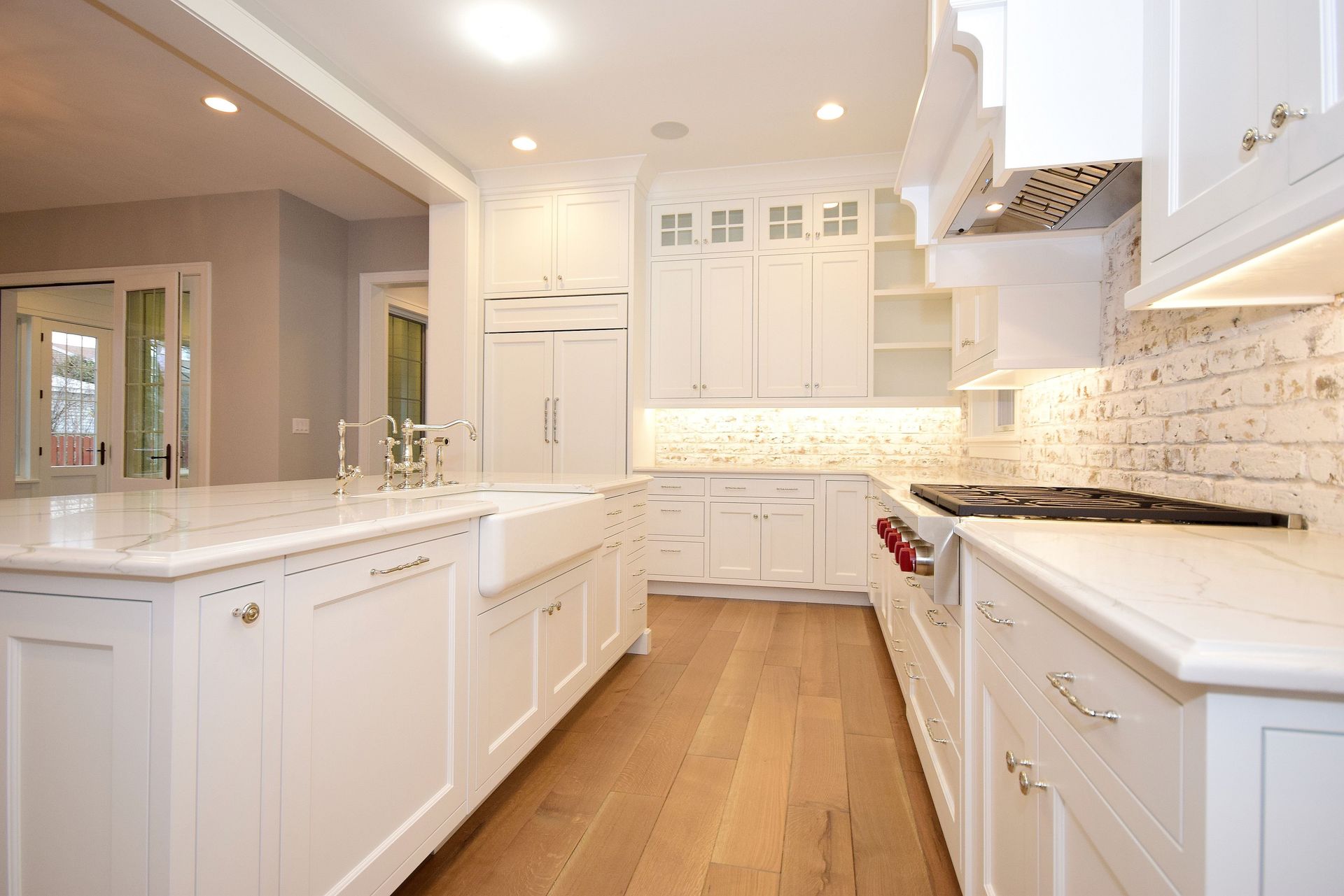 A kitchen with white cabinets , wooden floors , and a stove.