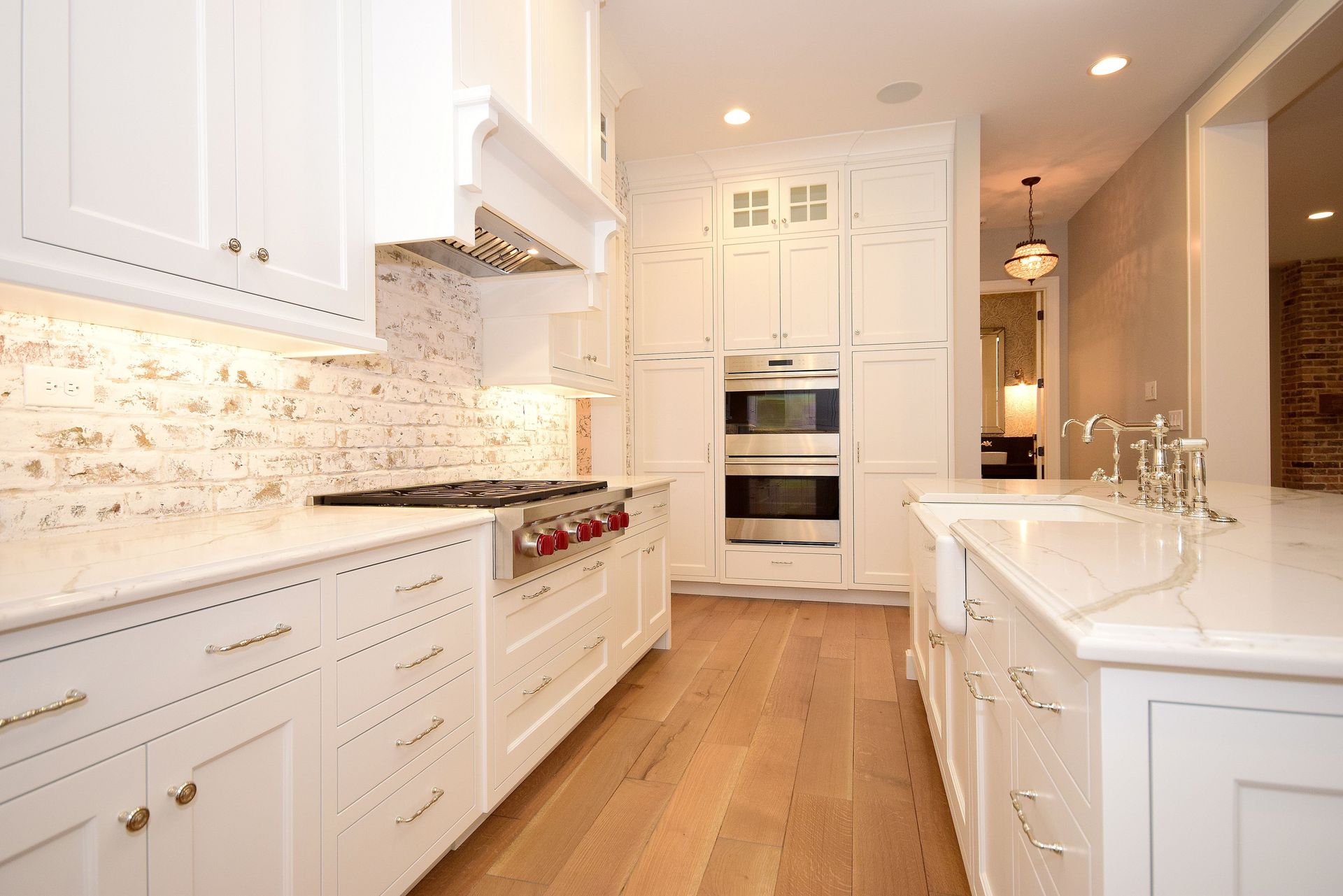 A kitchen with white cabinets and wooden floors