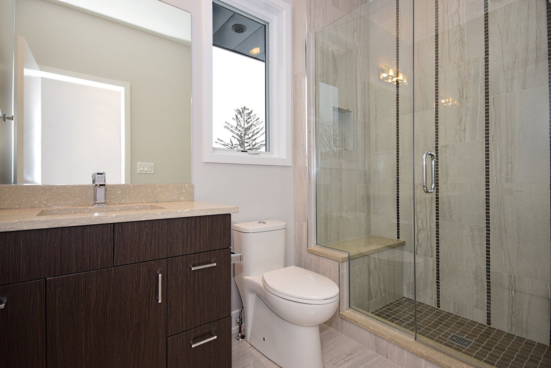 A bathroom with a toilet , sink and shower.