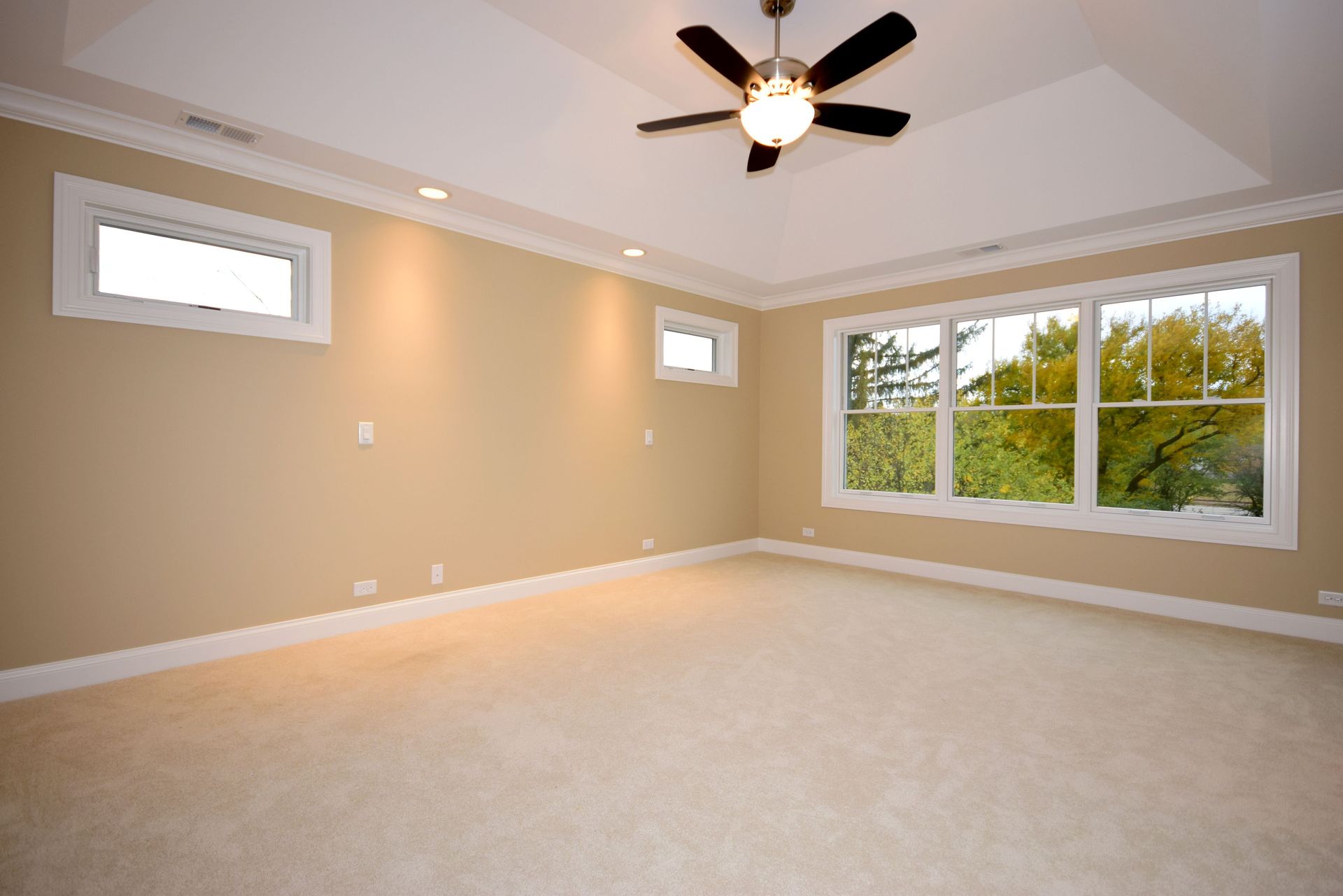 An empty room with a ceiling fan and a lot of windows