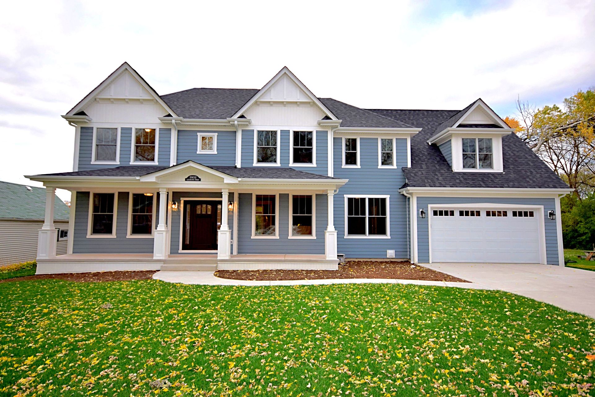 A large blue and white house with a large lawn in front of it
