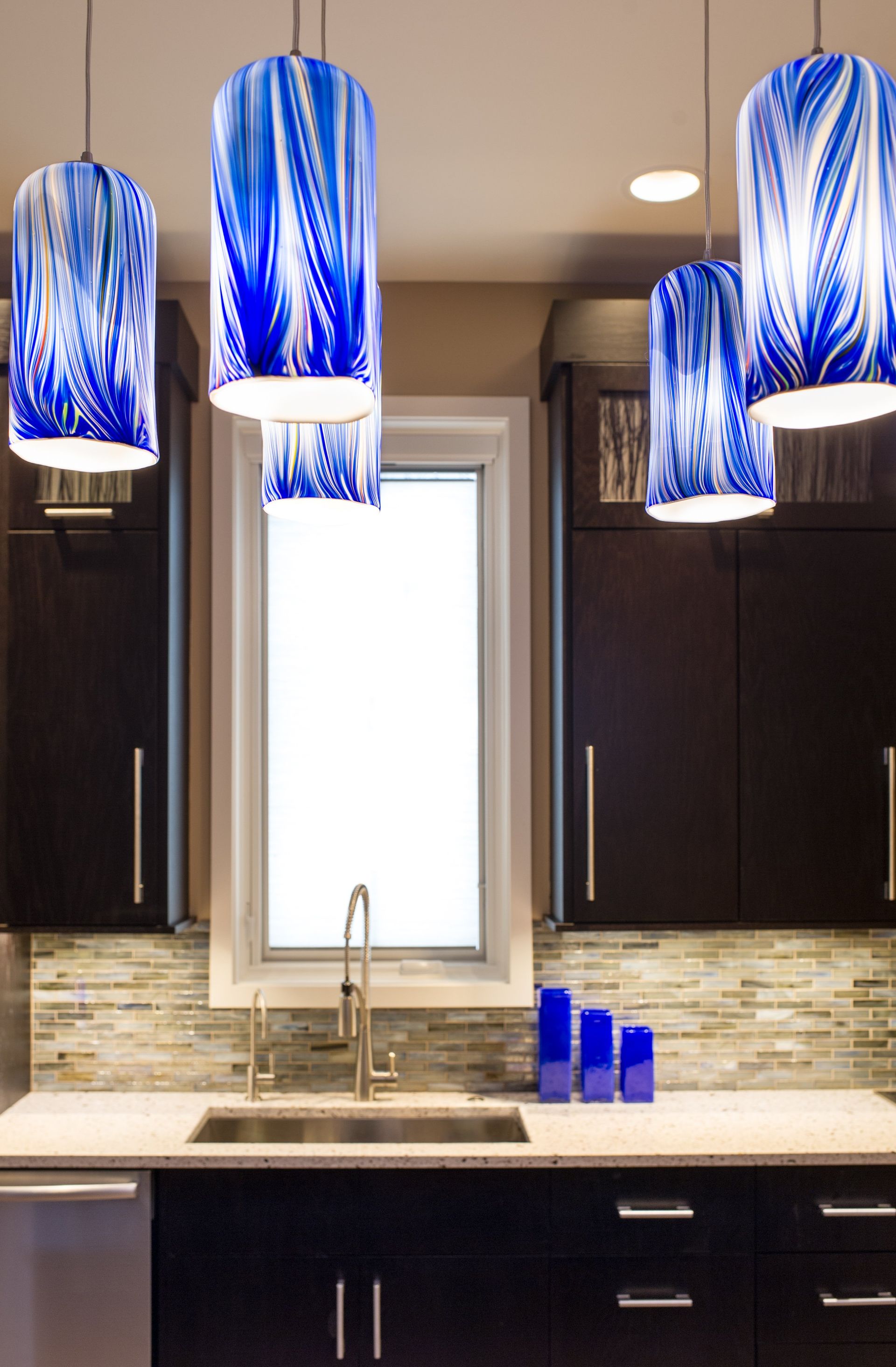 A kitchen with blue pendant lights hanging from the ceiling