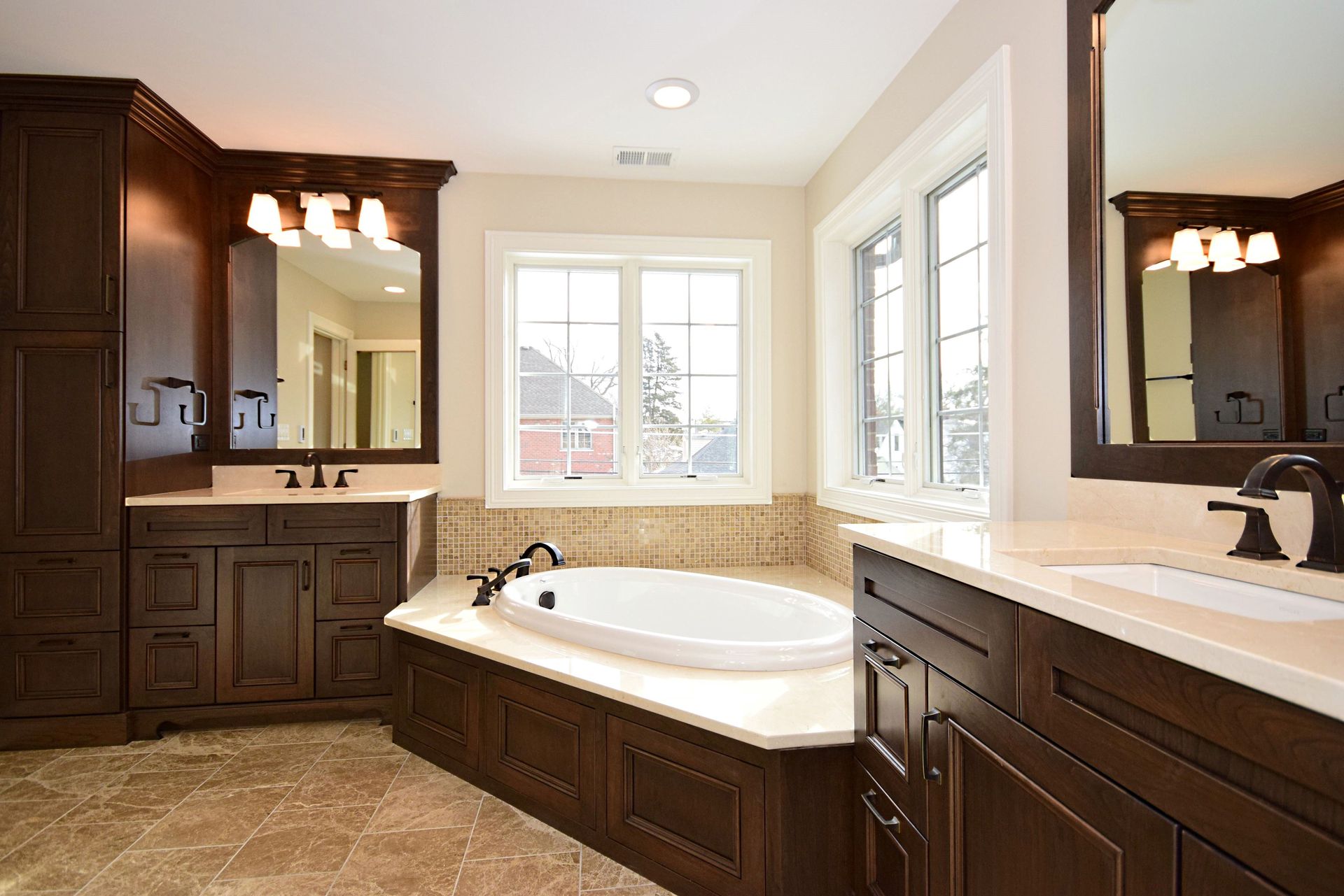 A bathroom with two sinks , a tub and two mirrors.