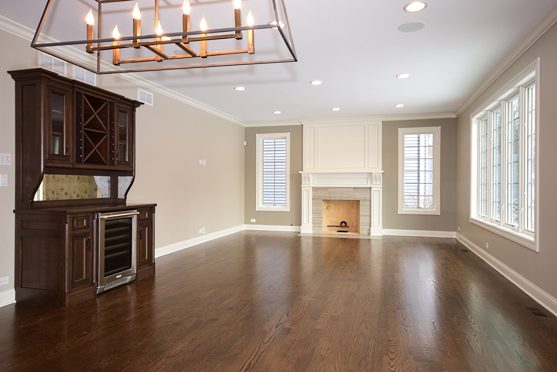 An empty living room with a fireplace and a chandelier