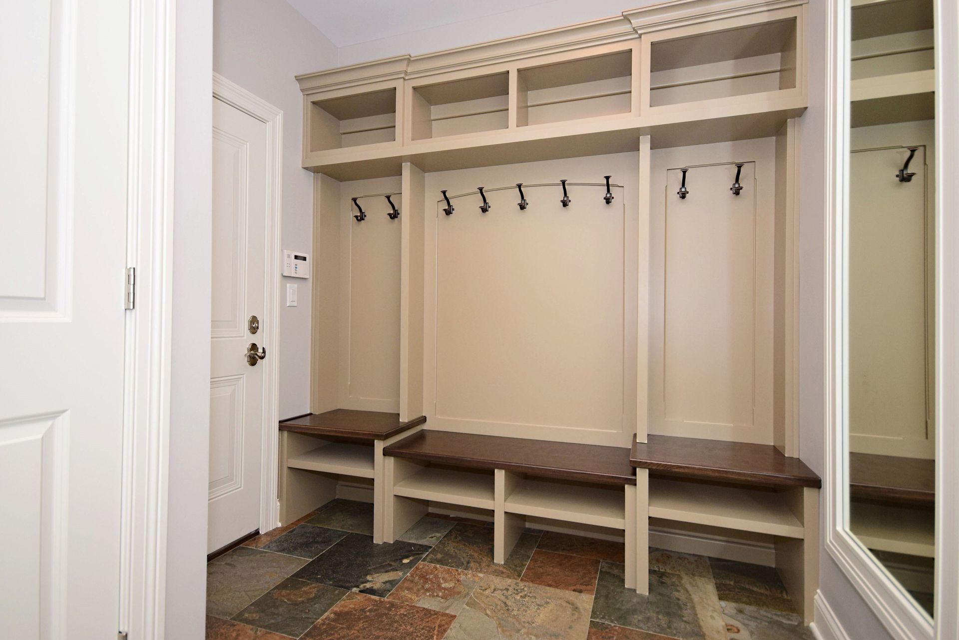 A mud room with a bench and a mirror.