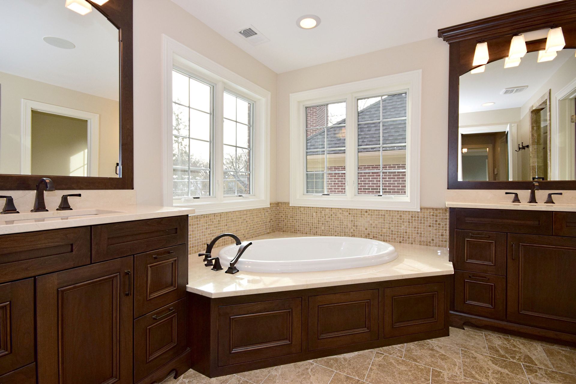 A bathroom with two sinks , two mirrors and a tub.