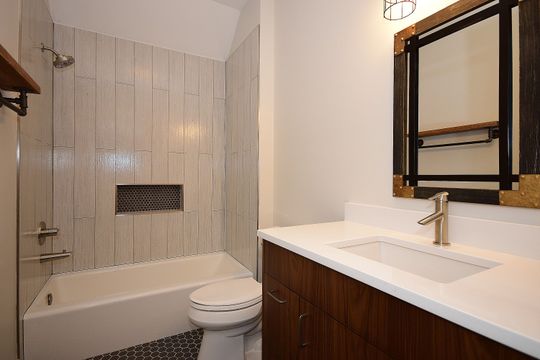 A bathroom with a sink , toilet , bathtub and mirror.