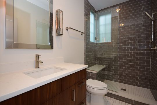 A bathroom with a toilet , sink , mirror and walk in shower