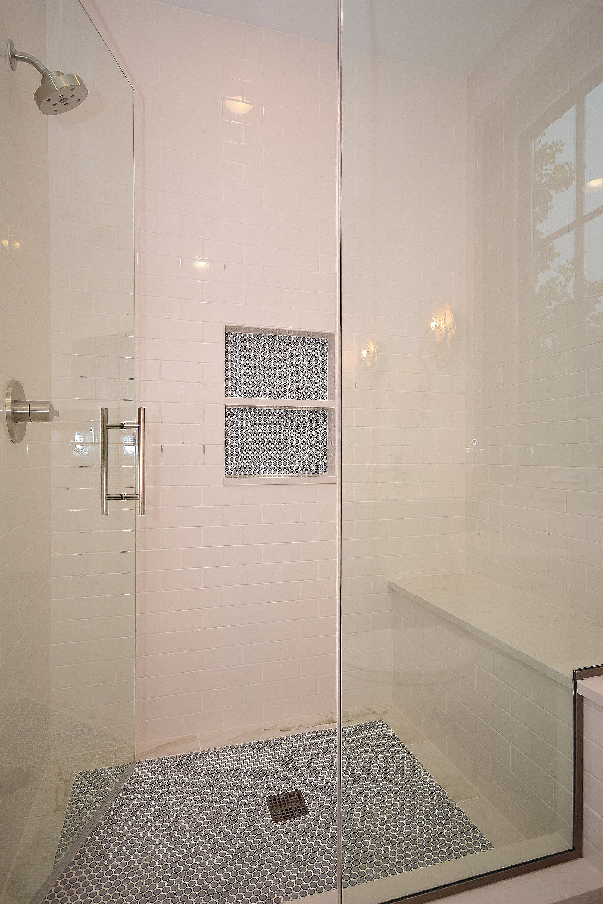 A walk in shower with a tiled floor and a glass door.