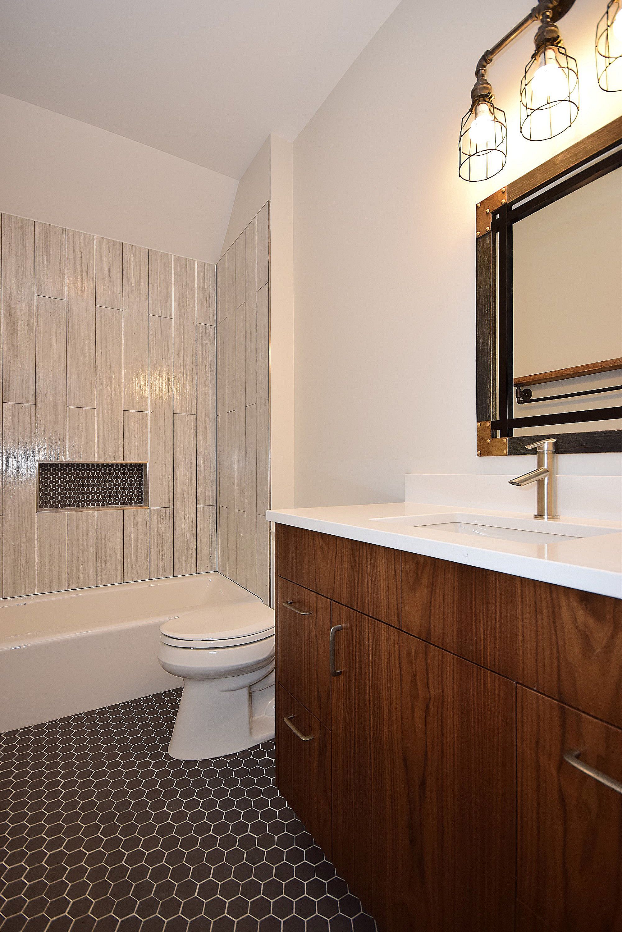 A bathroom with a toilet , sink , tub and mirror.