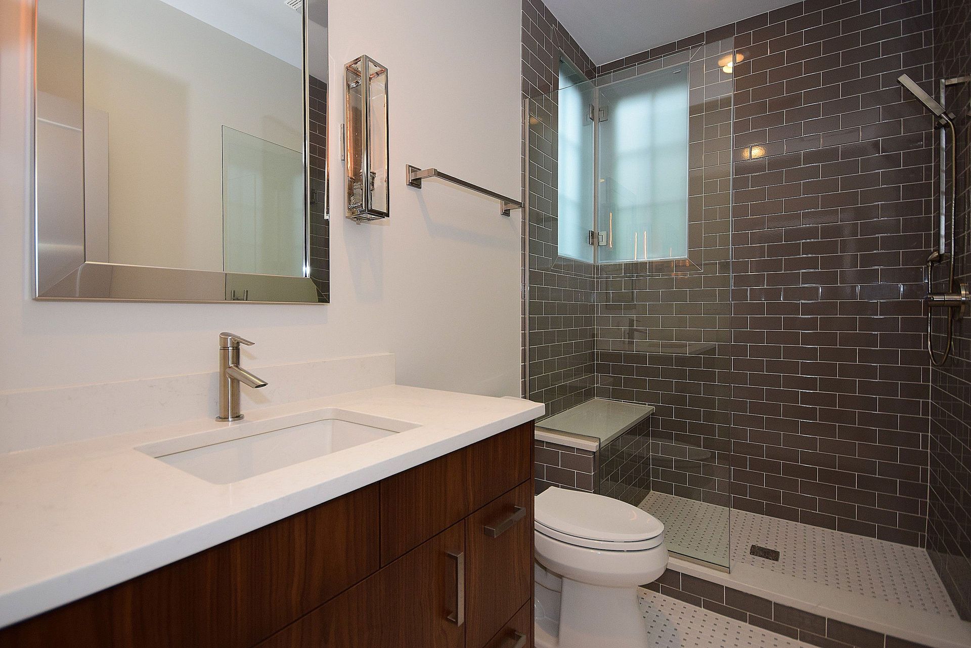 A bathroom with a toilet , sink , mirror and walk in shower