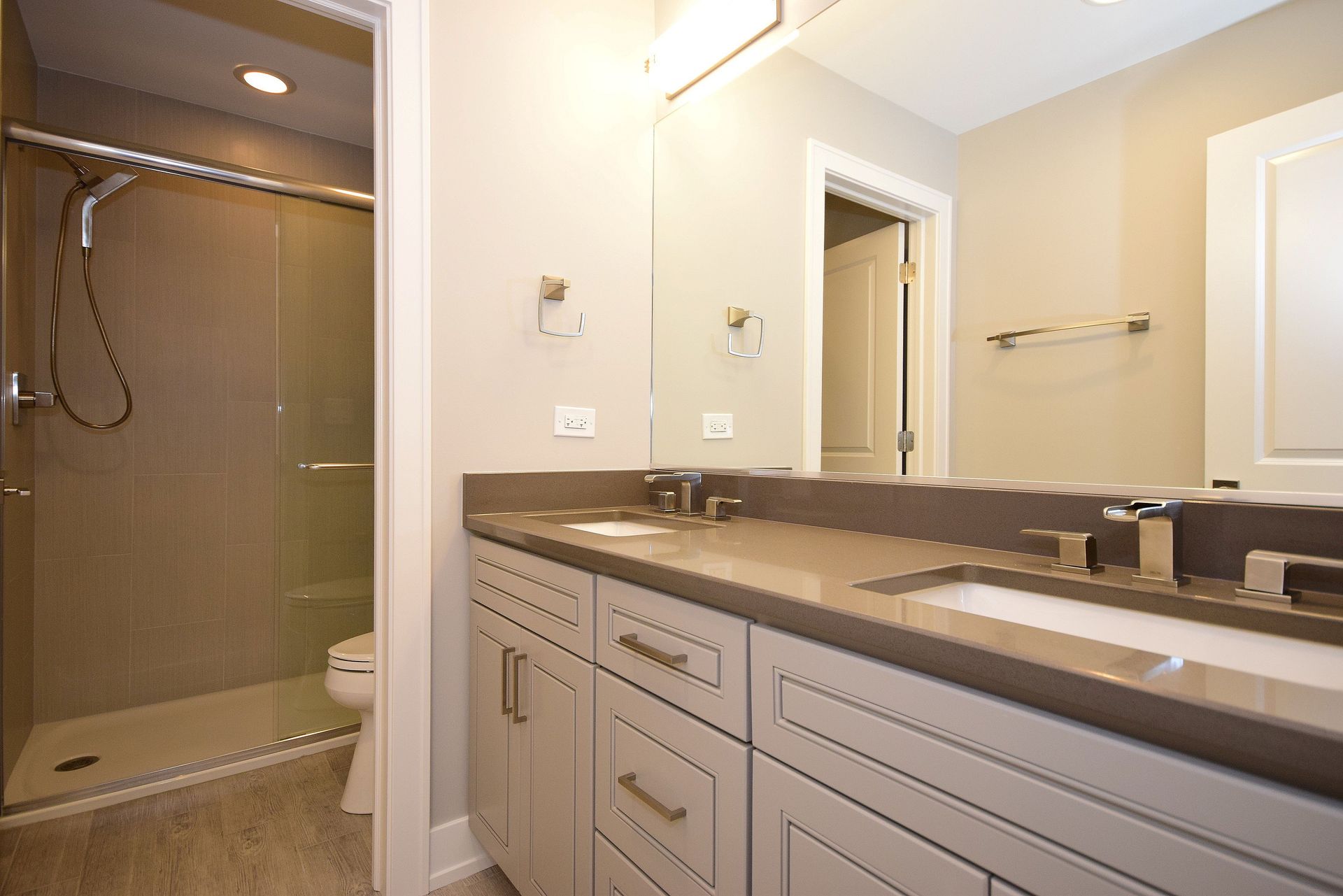 A bathroom with two sinks , a toilet and a shower.