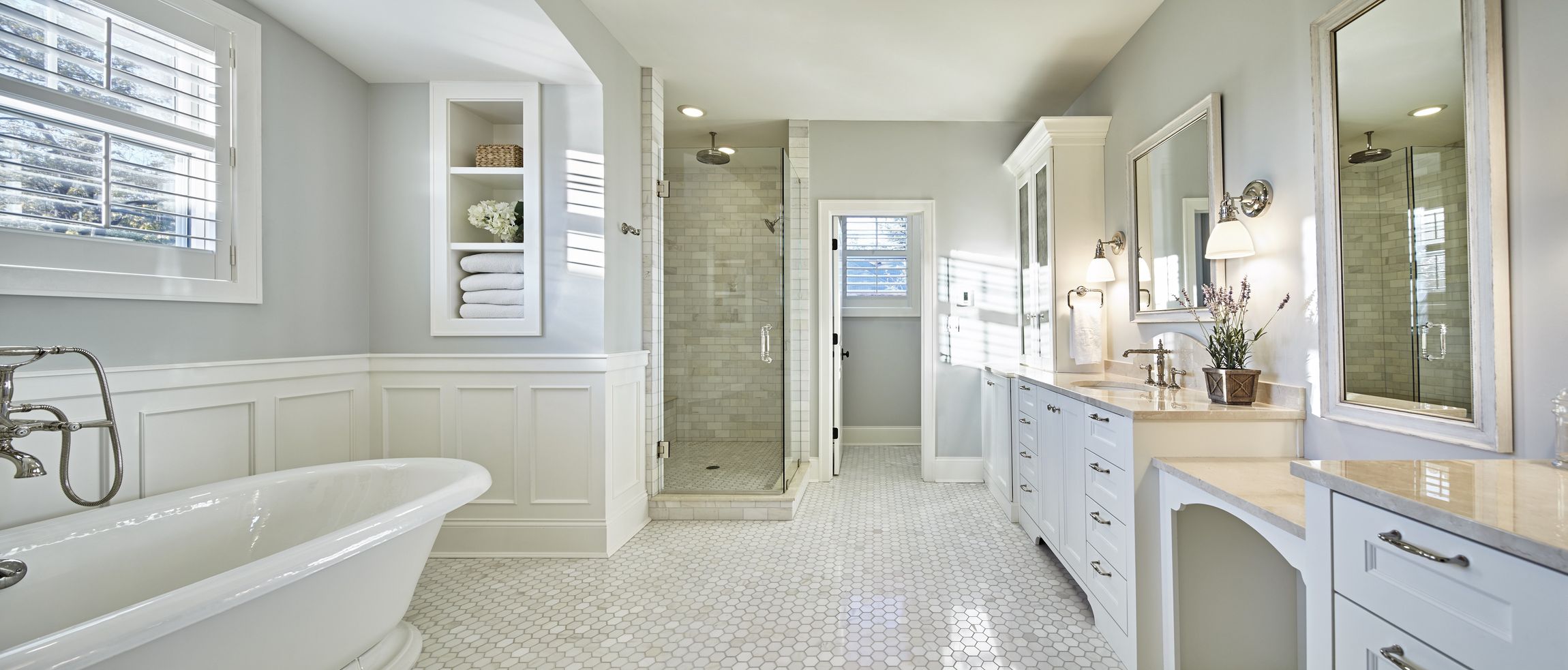 A bathroom with a bathtub , sinks , mirrors and a walk in shower.