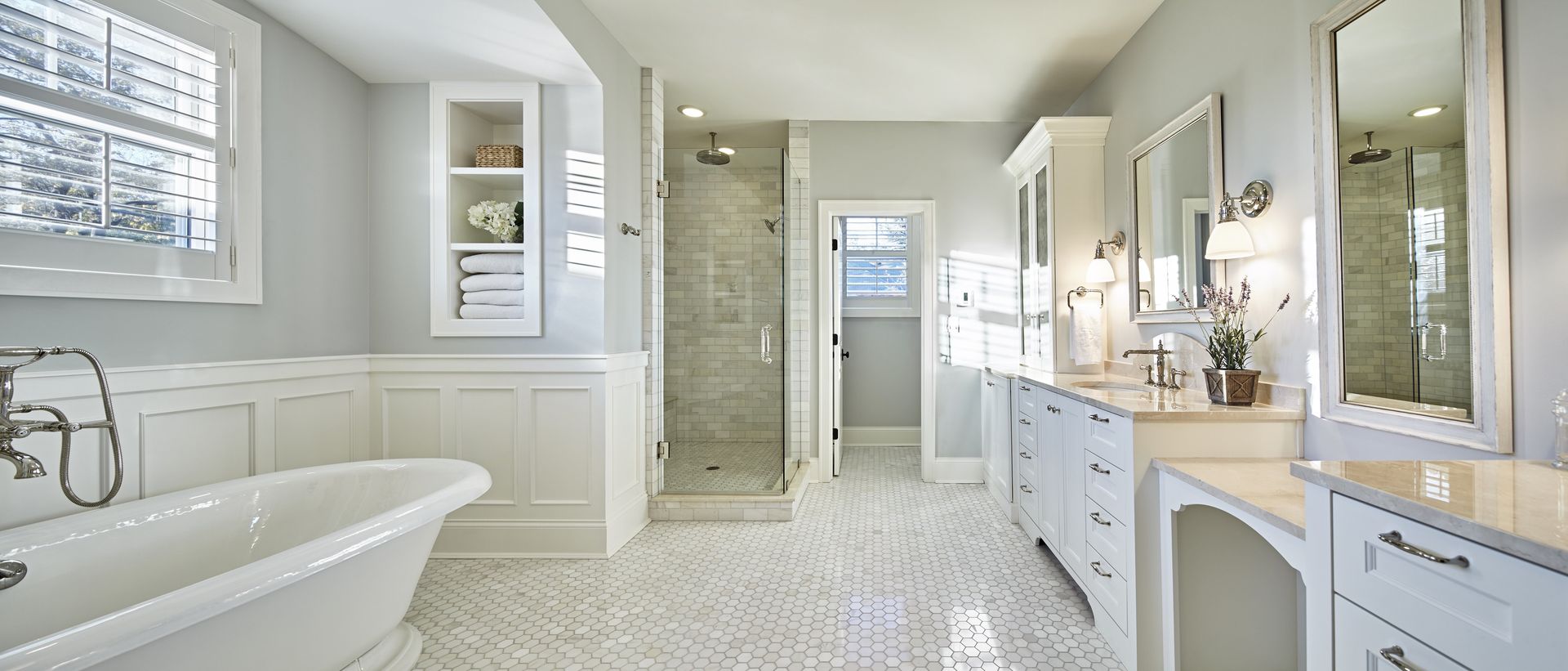 A bathroom with a bathtub , sinks , mirrors and a walk in shower.