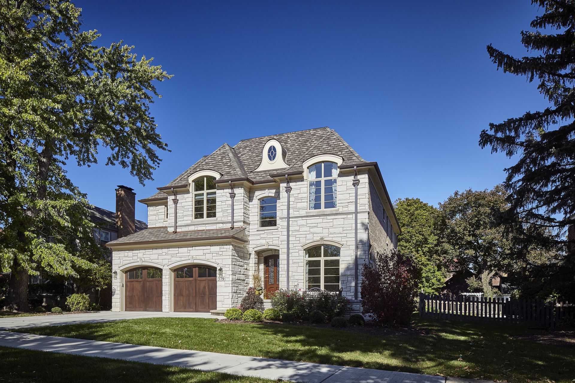 A large white brick house with a brown garage door